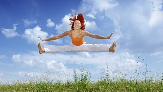 young woman red hair aerial splits blue sky background