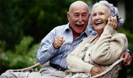 an older couple laughing and smiling while talking on cell phone