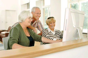 three seniors happily looking at computer monitor three seniors happily looking at computer monitor