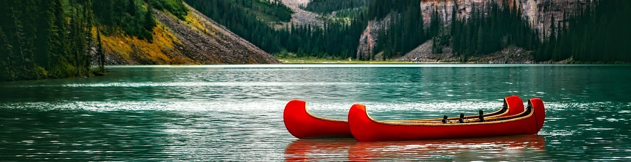 Two red canoes float on the water of Lake Louise 