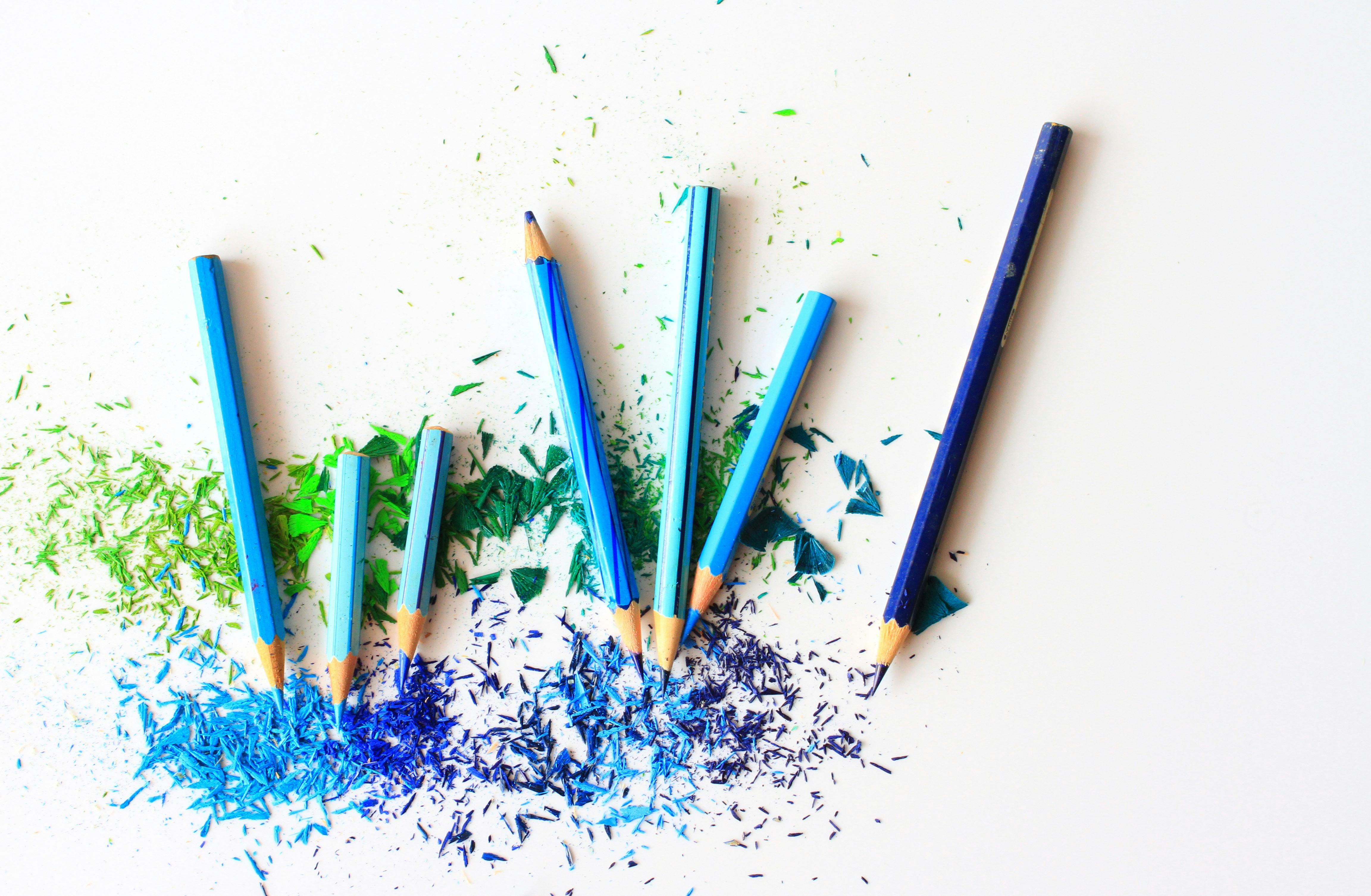 Various blue pencil crayons on a table with many fresh pencil shavings