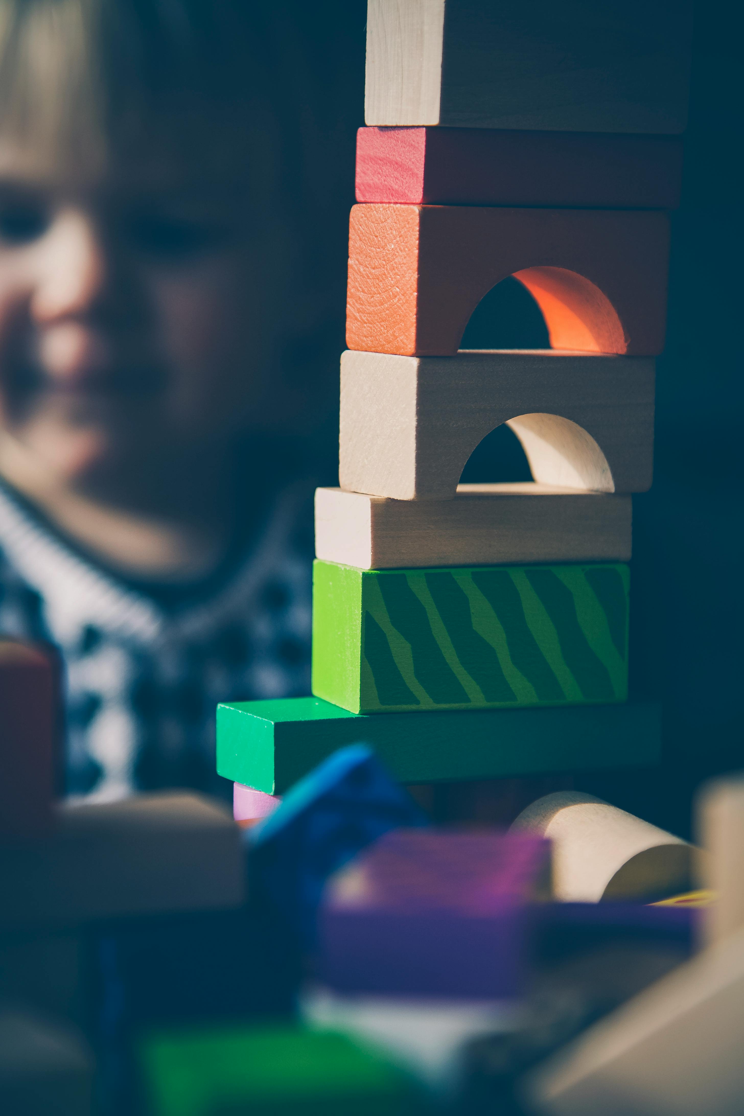 A child plays with and is stacking colourful wooden blocks