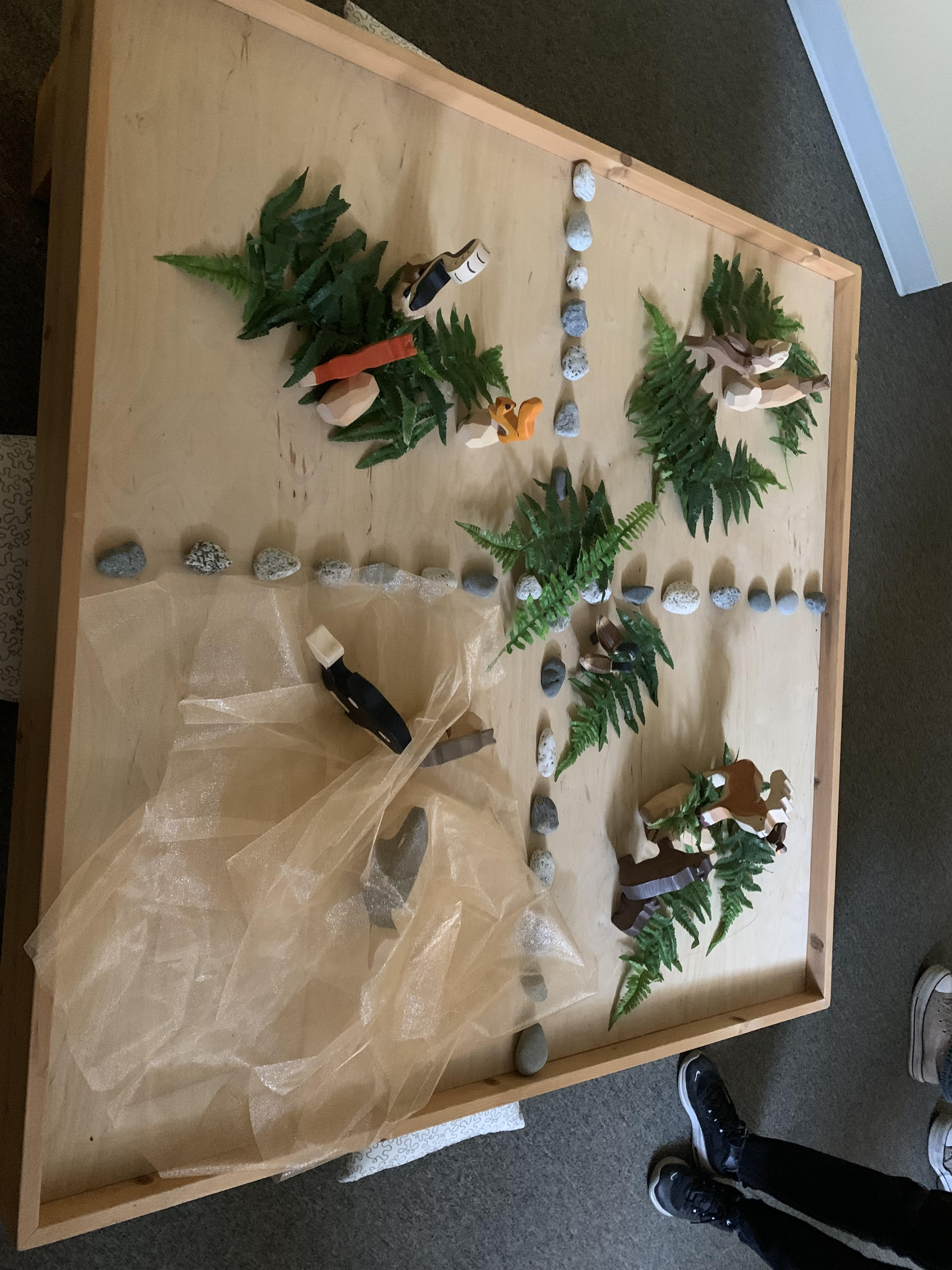 A table covered in brown Kraft paper is decorated with branches, rocks and other nature items