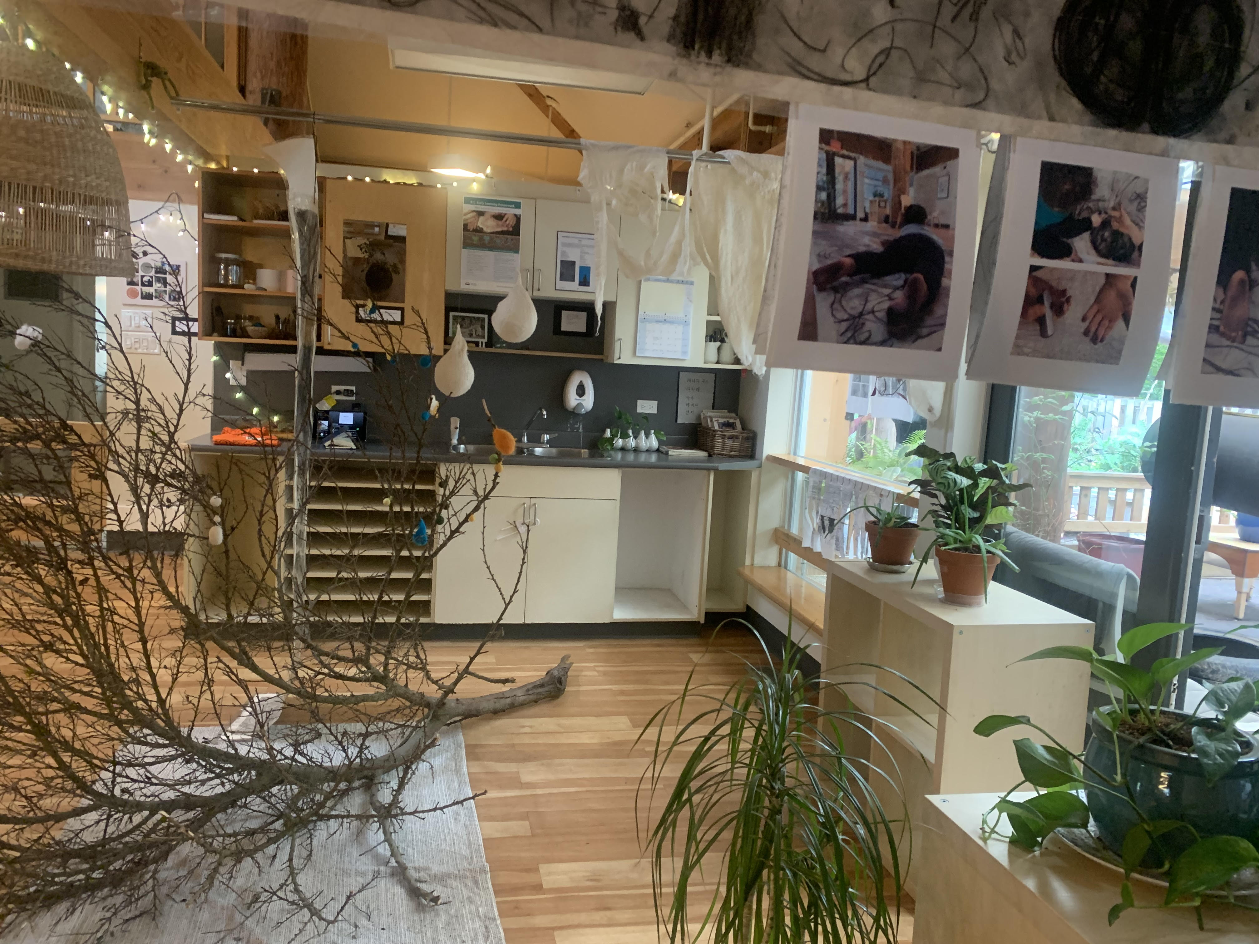 The inside of an ECE centre's kitchen area. The floors are wooden and upper and lower kitchen cupboards are white 