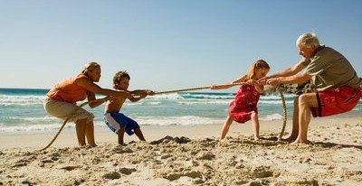 grandparents playing rope on beach with grandkids