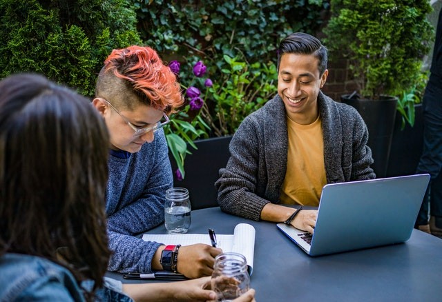 Three people with visibly diverse backgrounds, meeting outdoors in a casual setting