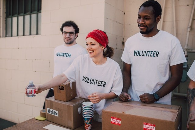 Image of three volunteers handing out medicine and water